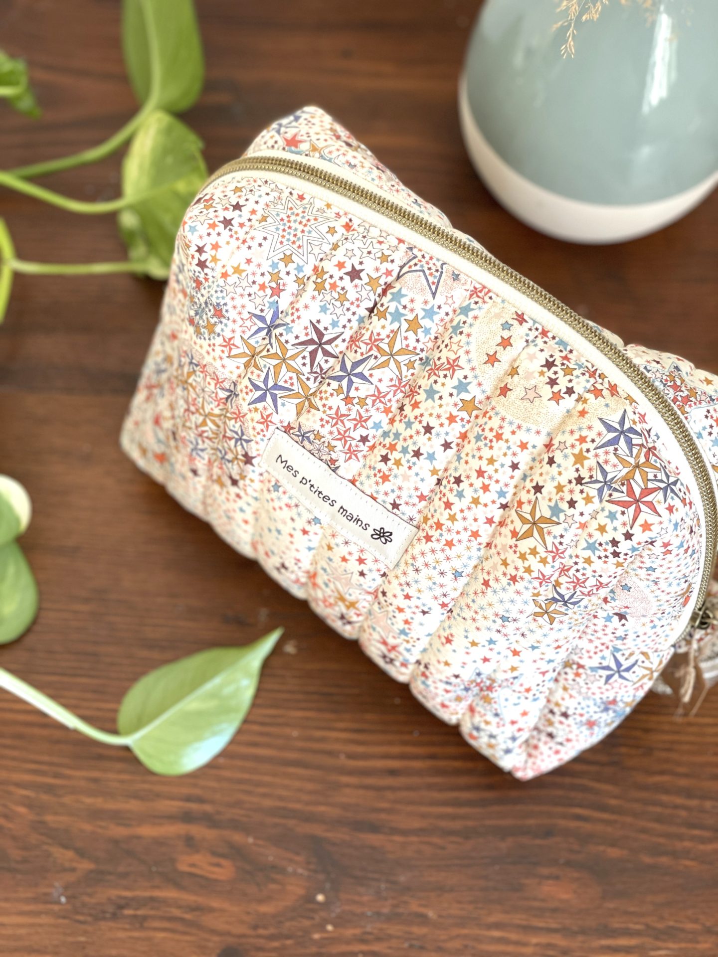 Trousse de toilette liberty matelassée au motif ciel étoilé multicolore sur fond écru. Zip descendant sur les côtés pour une ouverture large avec un curseur anneau an laiton. Petit noeud accroché au curseur cousu dans le liberty assorti. Entièrement doublée dans un coton de couleur cannelle.